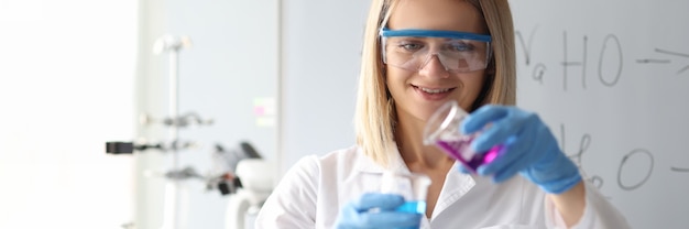 Kobieta Naukowiec W Okularach Ochronnych, Wylewanie Roztworu Chemicznego Z Kolby W Laboratorium Chemicznym
