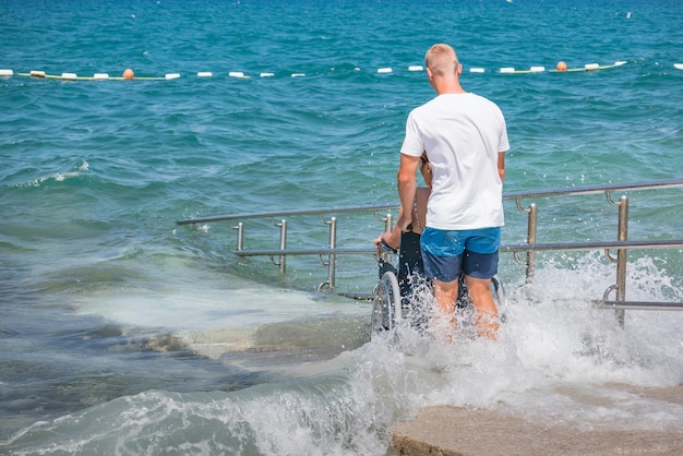 Kobieta niepełnosprawna na wózku inwalidzkim na dostępnej plaży pływa