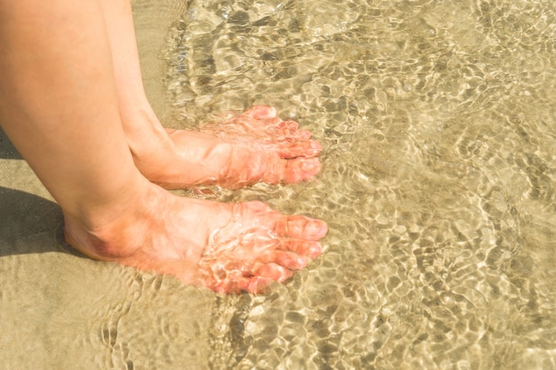 kobieta nogi w wodzie na plaży