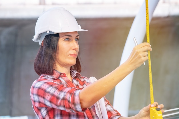 Kobieta nosi biały kapelusz bezpieczeństwa pracuje na budowie