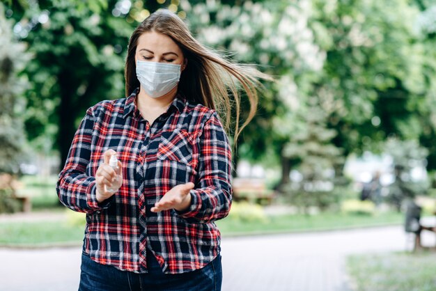 kobieta nosi maskę ochronną i mycie rąk w parku