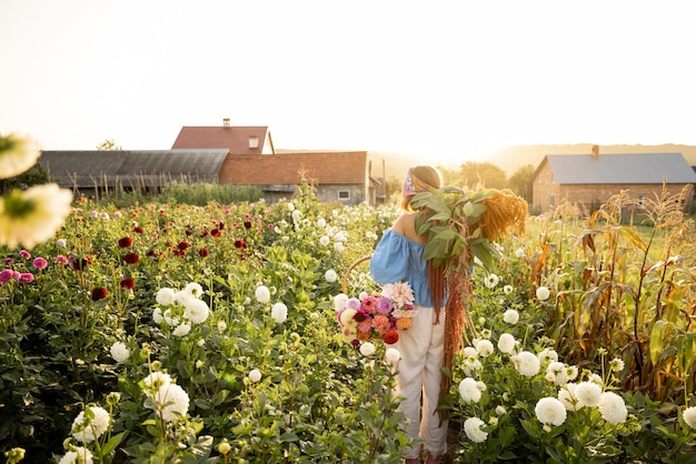 Kobieta nosi na farmie mnóstwo świeżo zebranych kwiatów