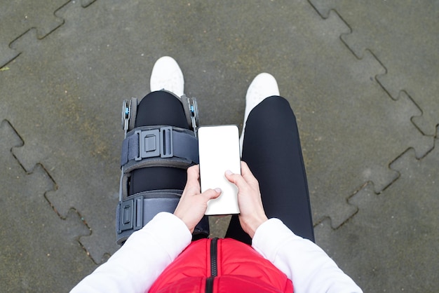 Kobieta nosząca ortezę kolana lub ortezę po operacji nogi ćwiczącej w parku