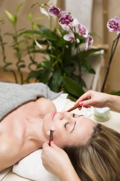 Kobieta o twarzy masażer rolki terapii w salonie