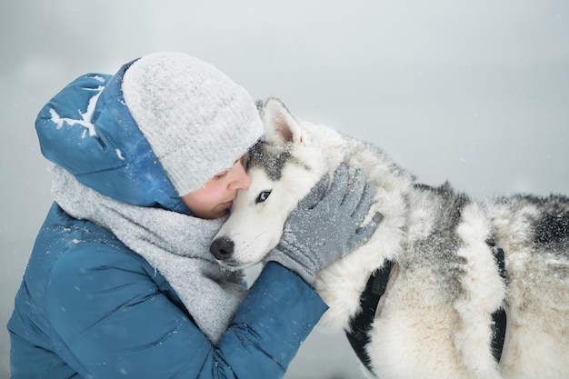 Kobieta Obejmująca śnieżny Siberian Husky W Zimie