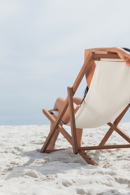 Kobieta odpoczywa na jej pokładu krześle przed oceanem