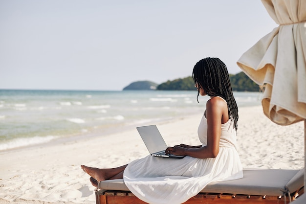 Kobieta odpoczywa na plaży z laptopem