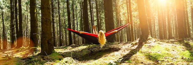 Kobieta odpoczywa w hamaku na świeżym powietrzu. Zrelaksuj się i ciesz się naturą w lesie
