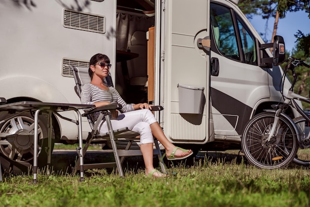 Kobieta odpoczywa w pobliżu samochodów kempingowych w przyrodzie. Rodzinne wakacje na wakacje, wyjazd na wakacje w kamperze RV, wakacje w przyczepie kempingowej.