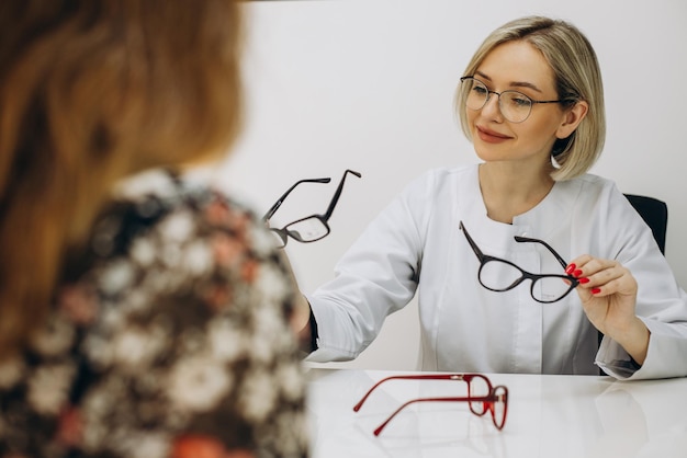 Kobieta okulista w sklepie optycznym pomaga wybrać okulary