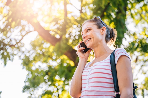 Zdjęcie kobieta opowiada na telefonie komórkowym w parku