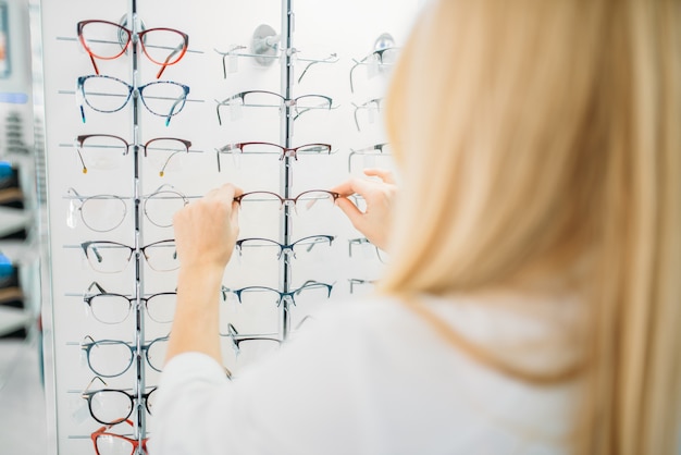 Zdjęcie kobieta optometrysta pokazuje okulary w sklepie optycznym