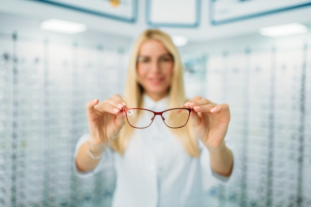 Kobieta Optyk Pokazuje Okulary W Sklepie Optycznym. Dobór Okularów Z Profesjonalnym Optometrystą