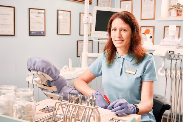 Kobieta ortodonta siedzi przy stole w gabinecie stomatologicznym