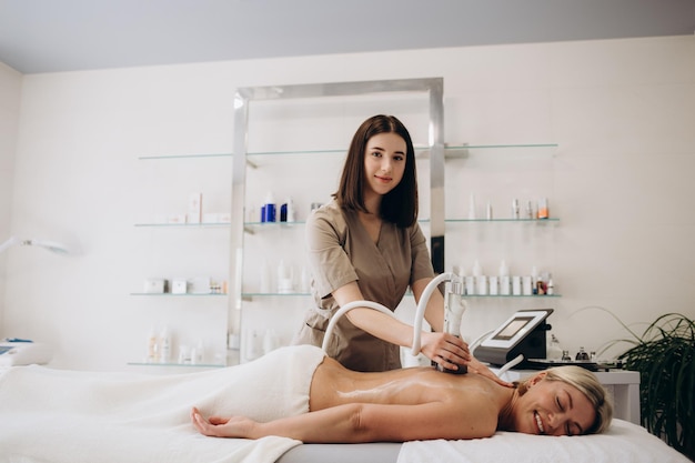 Kobieta otrzymująca próżniowy masaż rolkowy na plecach w medycznym centrum kosmetycznym Procedura masażu drenażu limfatycznego