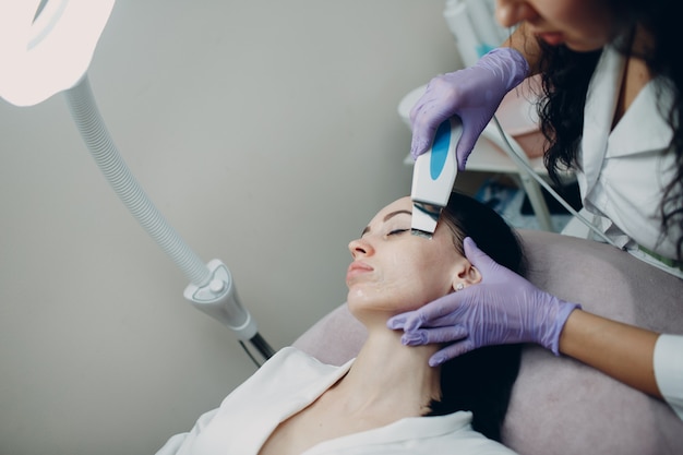 Kobieta otrzymująca terapię oczyszczającą za pomocą profesjonalnego sprzętu ultradźwiękowego w kosmetologii beauty spa.