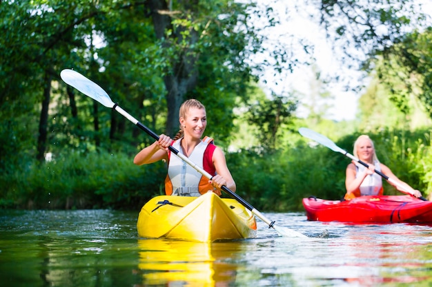 Zdjęcie kobieta paddling z czółnem na lasowej rzece