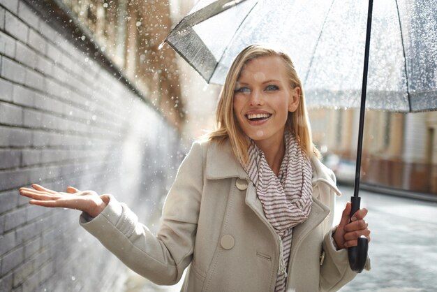 Zdjęcie kobieta parasol i ręka z deszczem w mieście spacery i niespodzianka dla splash pogody i szczęśliwy w zimie osoba wow i uśmiech z podróży podróży i podekscytowany wodą na chodniku w kapsztadzie