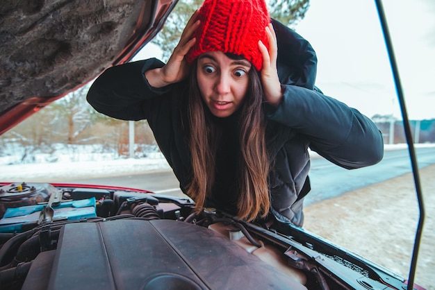 Kobieta patrząca na koncepcję pomocy drogowej silnika samochodu w sezonie zimowym