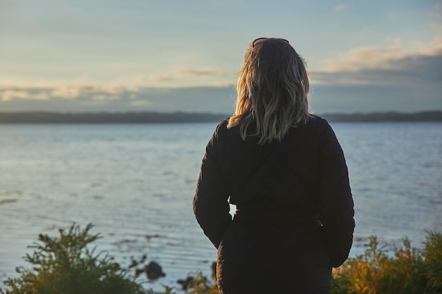 Kobieta patrząca na morze w Danii o zachodzie słońca