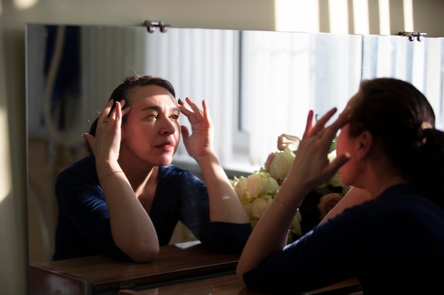 Zdjęcie kobieta patrząca na zmarszczki w lustrze