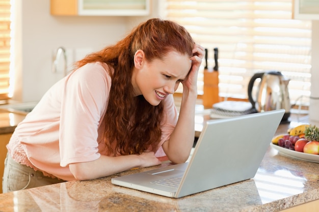 Kobieta patrzeje wprawiać w zakłopotanie przy jej laptopem
