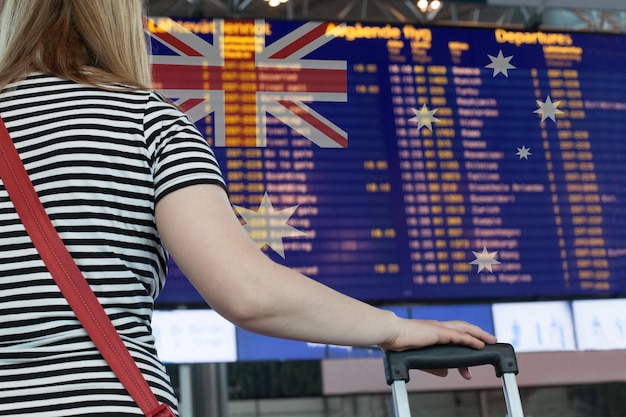 Kobieta patrzy na tablicę wyników na lotnisku Wybierz kraj Australia dla podróży lub migracji