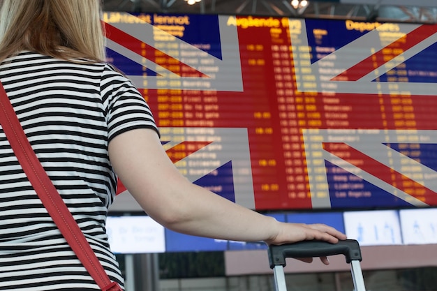 Kobieta patrzy na tablicę wyników na lotnisku Wybierz kraj do podróży lub migracji
