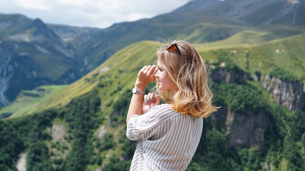 Kobieta piesze wycieczki w góry w czasie słonecznego dnia. Widok Kazbegi, Gruzja. Piękne naturalne górskie tło