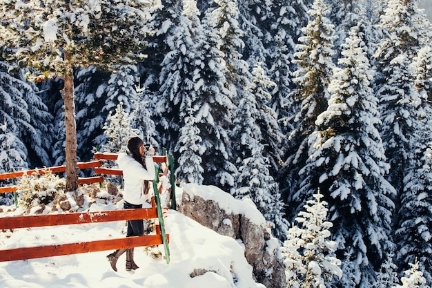 Zdjęcie kobieta pijąca herbatę stojąca na pokrytej śniegiem górze