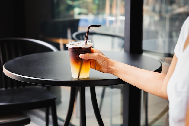 Zdjęcie kobieta pijąca lodową kawę w plastikowym kubku na stoliku w kawiarni na świeżym powietrzu