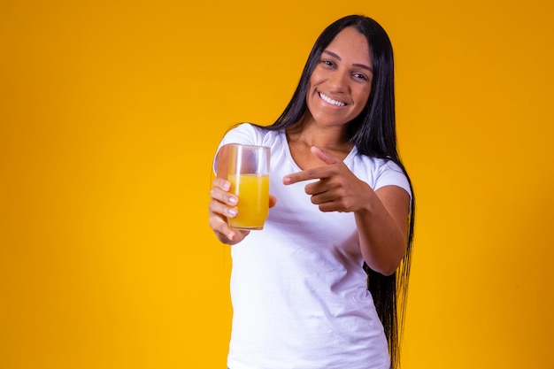 Kobieta pijąca sok pomarańczowy w żółtym tle