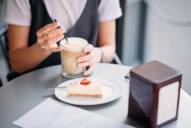 Kobieta pije coffe i je tort przy stołem kawiarnia w letnim dniu plenerowym