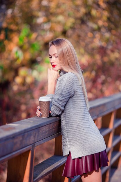 Kobieta pije kawę w jesień parku