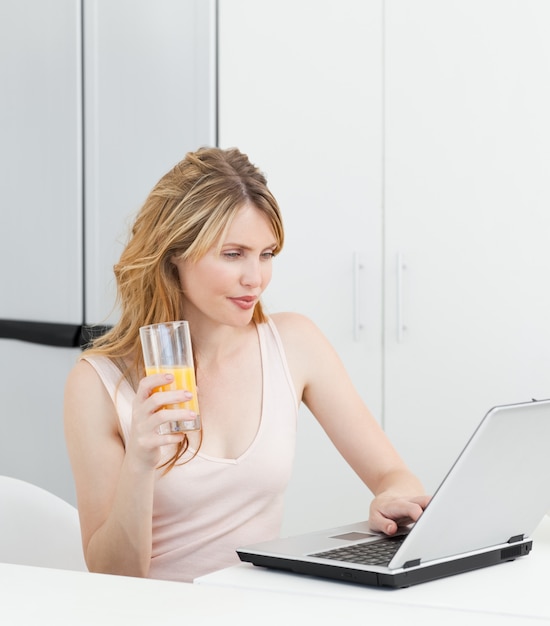 Kobieta Pije, Podczas Gdy Ona Patrzy Na Jej Laptopa