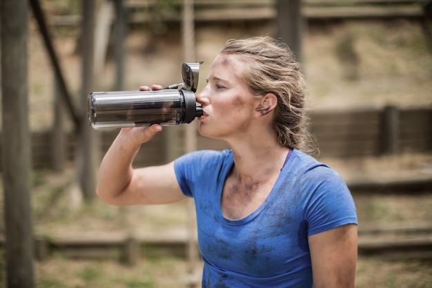 Kobieta pije wodę z butelki podczas toru przeszkód w obozie