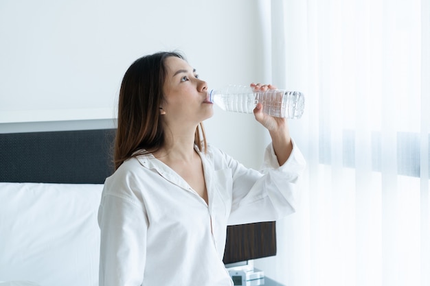 Kobieta pije wodę z przezroczystej plastikowej butelki