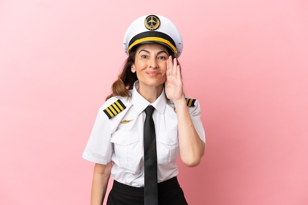 Kobieta pilotka samolotu w średnim wieku na białym tle na różowym tle krzycząca z szeroko otwartymi ustami