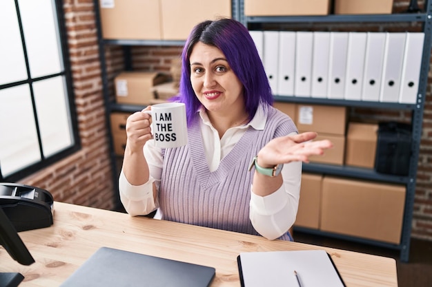 Kobieta plus size z fioletowymi włosami pracująca w małym biznesie e-commerce trzymająca puchar szefa świętujący osiągnięcie z radosnym uśmiechem i wyrazem twarzy zwycięzcy z podniesioną ręką