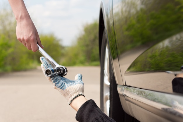 Kobieta podająca klucz nasadowy lub klucz maszynowy mechanikowi pracującemu pod jej samochodem