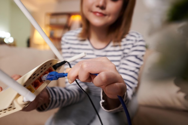 Kobieta podłącza kabel Ethernet do modemu