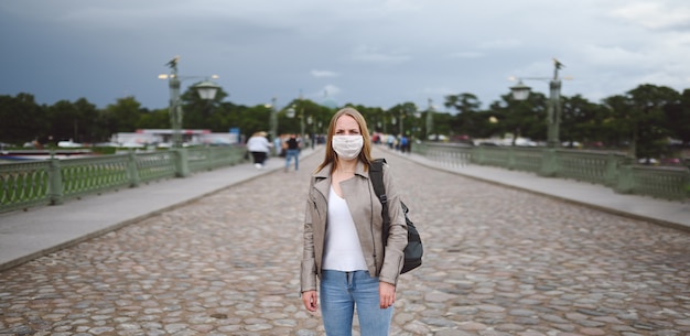 Zdjęcie kobieta podróżniczka z plecakiem i maską medyczną