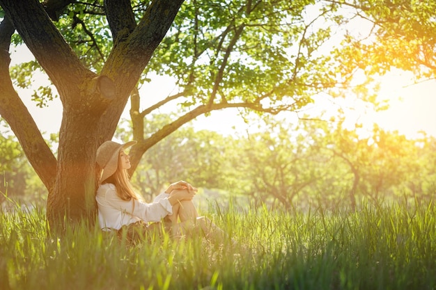 Kobieta podróżnik z plecakiem i kapeluszem siedzi w niesamowitym lesie wanderlust podróż koncepcja miejsca na tekst atmosferyczny moment dzień ziemi