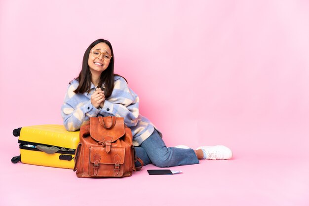 Kobieta podróżnik z walizką, siedząc na podłodze ze śmiechu