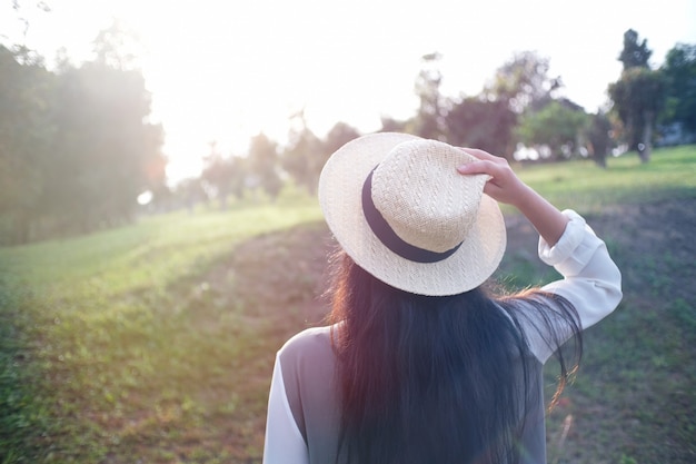 Kobieta podróżnika mienia kapelusz. patrząc na las.