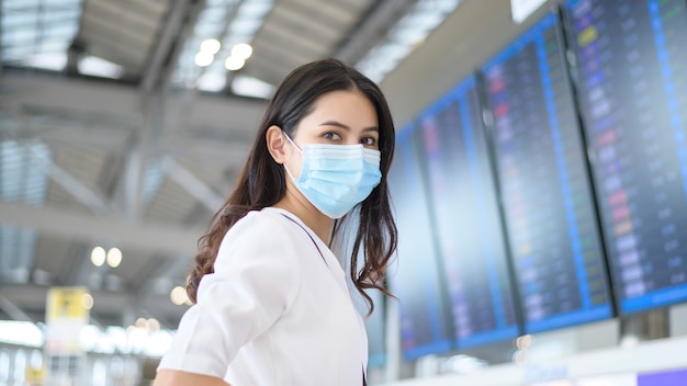 Kobieta podróżująca nosi maskę ochronną na międzynarodowym lotnisku, podróżuje w czasie pandemii Covid-19, podróże bezpieczeństwa, protokół zachowania dystansu społecznego, nowa koncepcja normalnej podróży