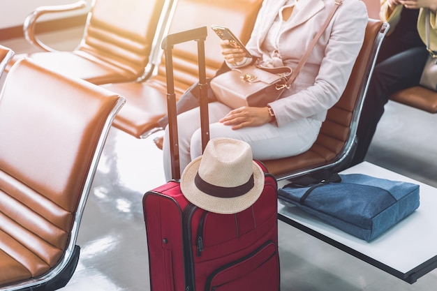 Kobieta podróżująca pasażerem podróżującym za pomocą smartfona, czekająca na lot wakacyjną wycieczkę na lotnisku po otwartym kraju