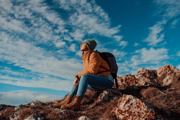 Kobieta podróżująca wolnością siedząca na szczycie gór i ciesząca się wspaniałą naturą