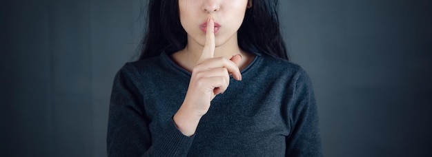 Kobieta pokazująca znak ciszy gestem wkładania palca do ust
