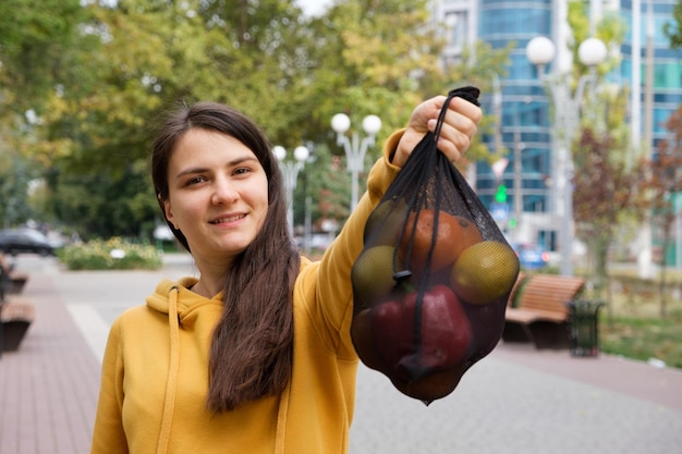 Kobieta pokazuje czarną przezroczystą torbę z owocami